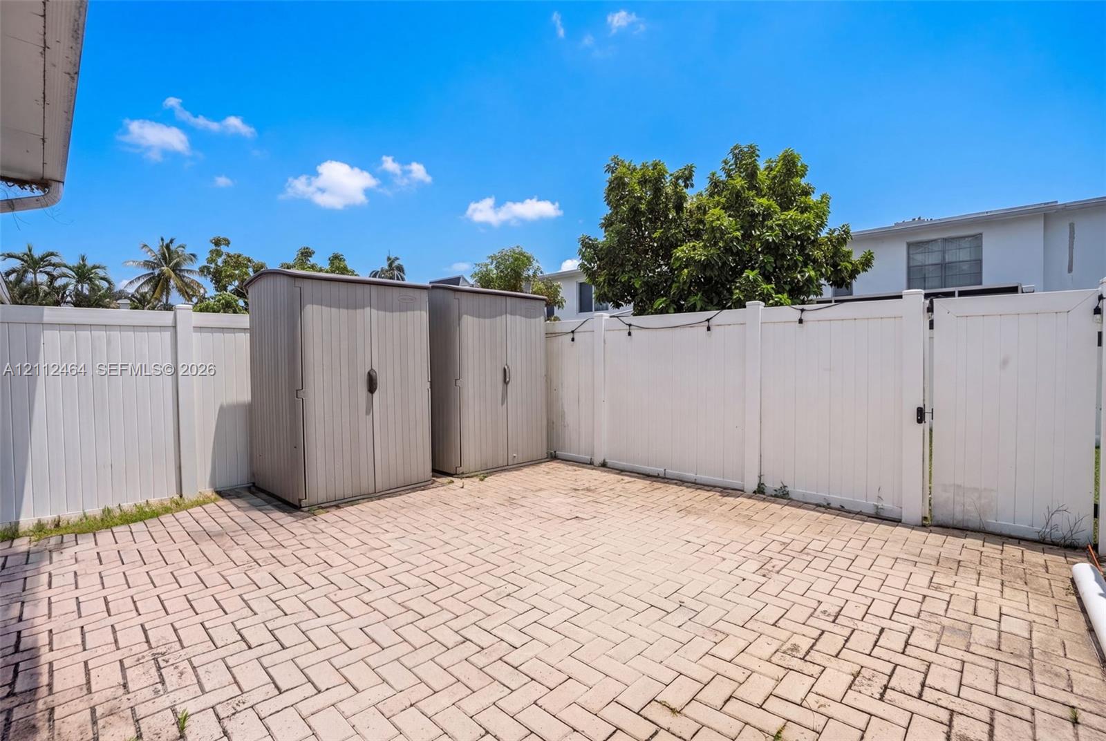 Private outdoor space featuring herringbone-patterned paver flooring and full-perimeter vinyl privacy fencing
