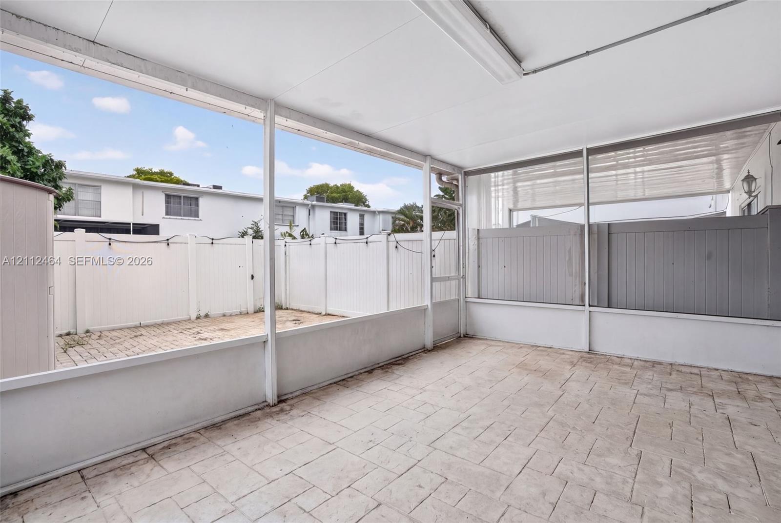 Screened-in patio featuring a solid roof, stamped concrete flooring, and a private enclosed outdoor area with vinyl privacy fencing