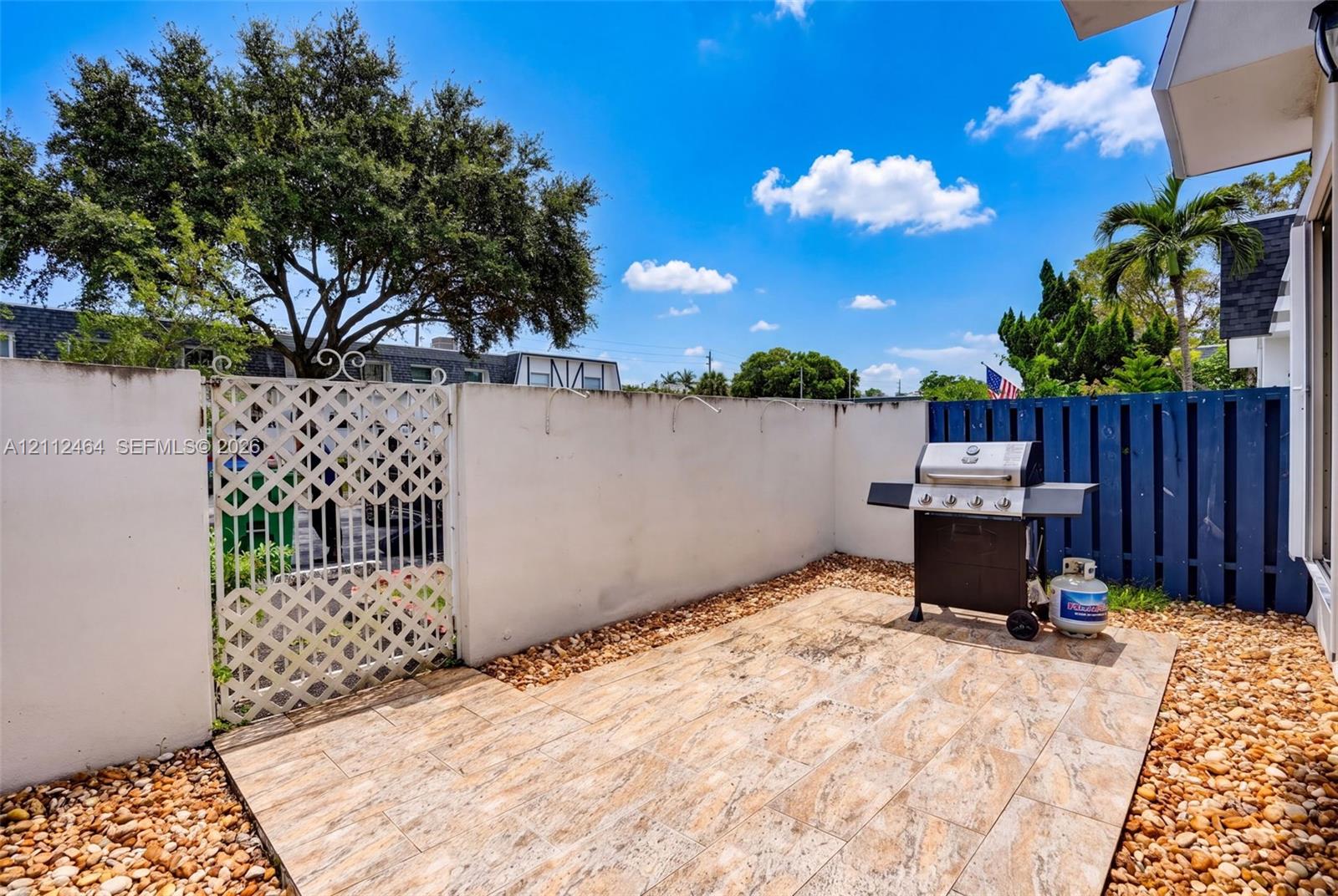 Private courtyard featuring a paved patio area, stucco perimeter walls, and an ornate metal gate Private courtyard featuring a paved patio area, stucco perimeter walls, and an ornate metal gate