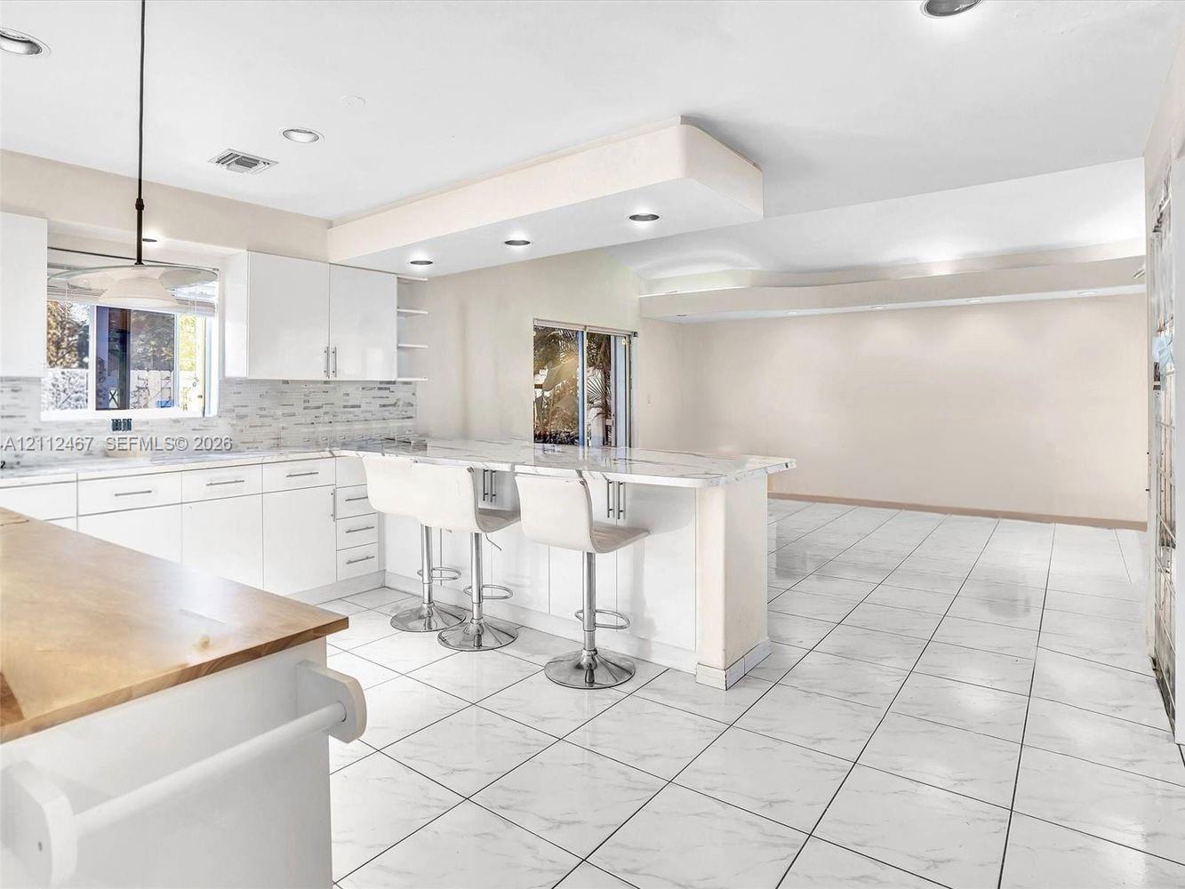 Kitchen featuring white cabinetry, stone-finish countertops, stone tile backsplash, recessed lighting, and tile flooring