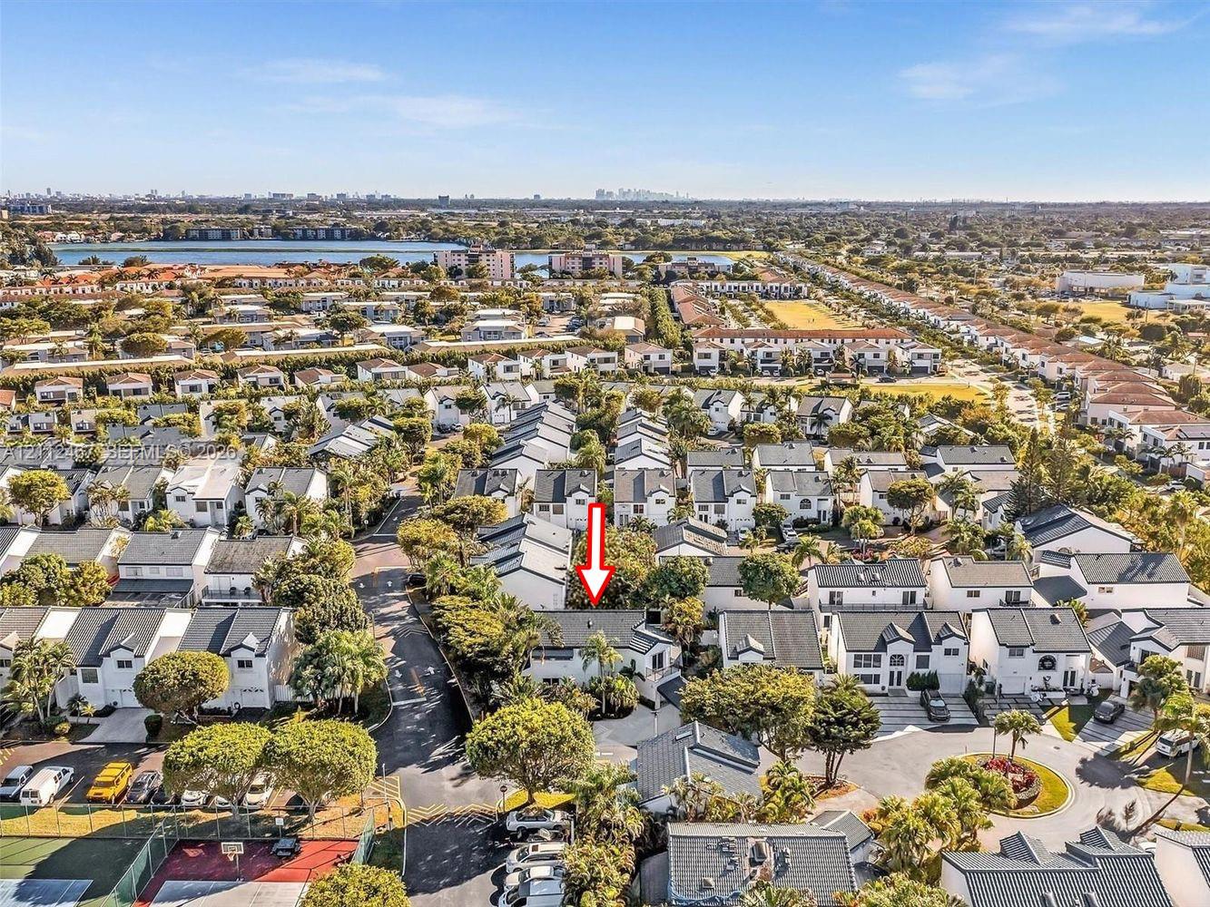 Aerial perspective of a multi-family residential community featuring mature landscaping, paved roadways, and proximity to regional water features