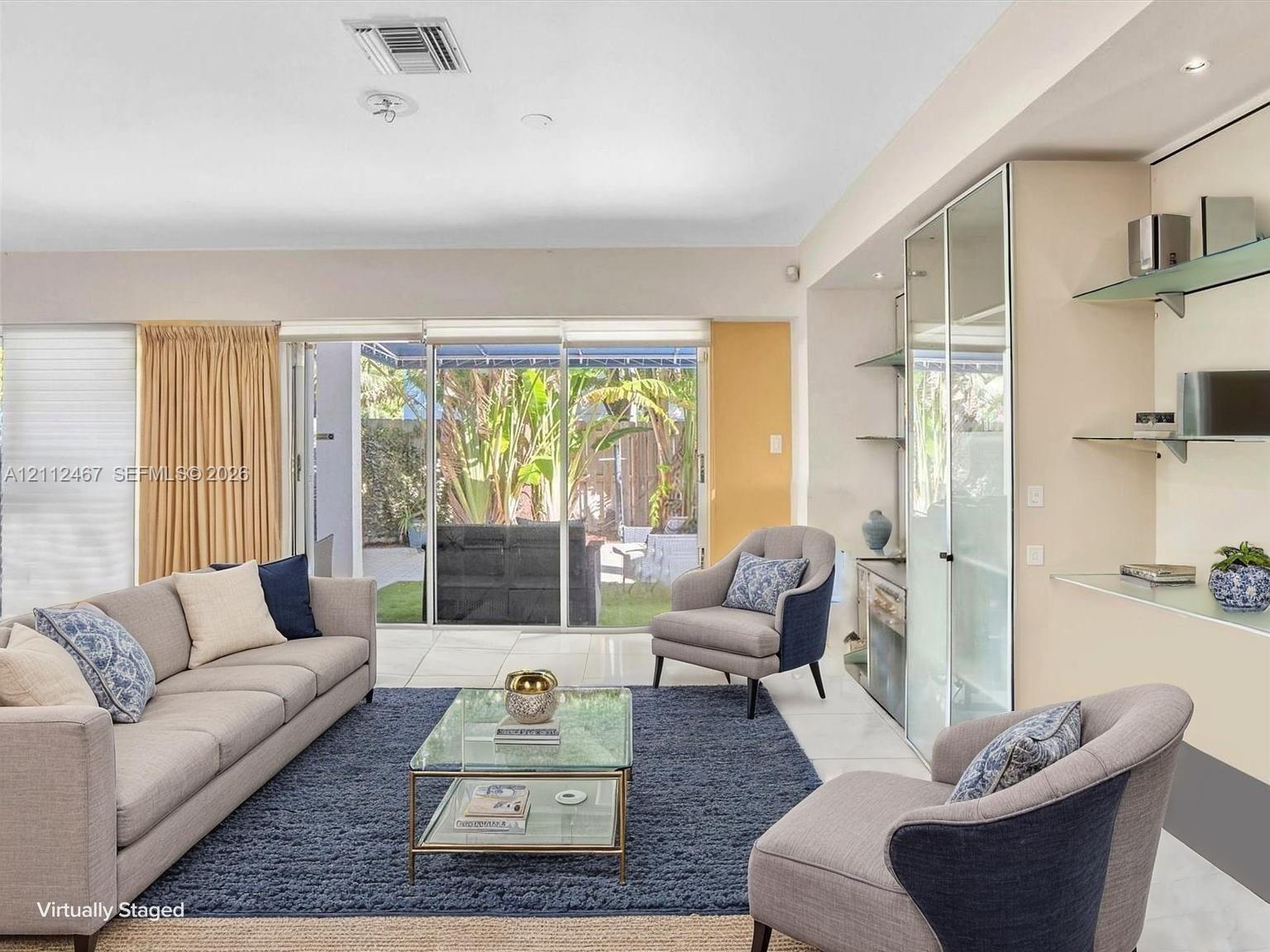 Living space featuring large sliding glass doors, built-in display cabinetry with glass shelving, and light-tone tile flooring