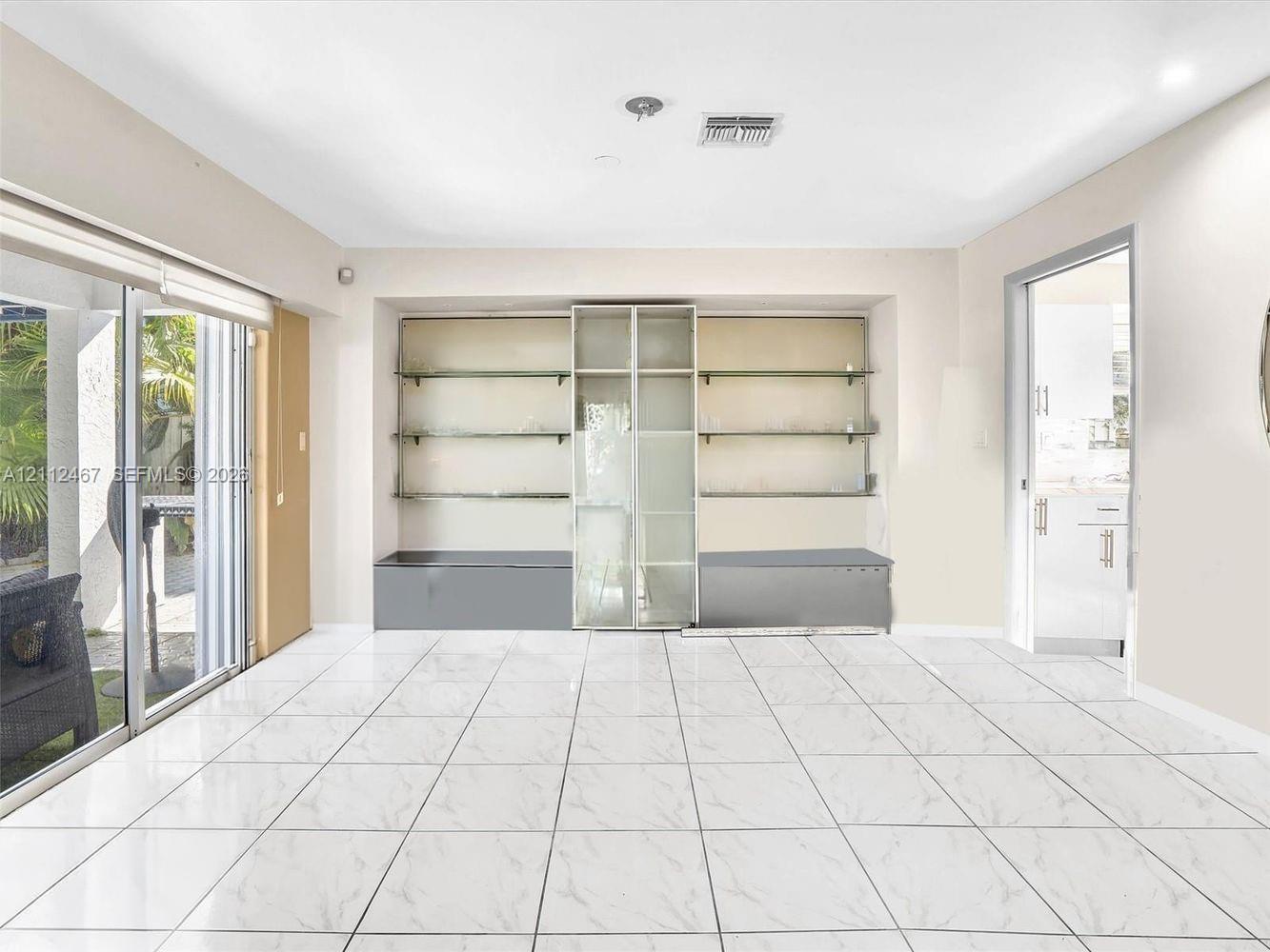 Large-format tile flooring, built-in shelving unit with glass partitions, and full-height sliding glass doors
