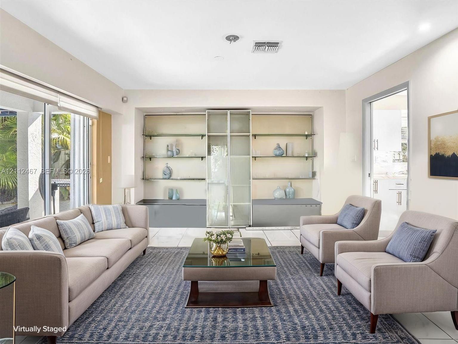 Living space featuring large format tile flooring, built-in recessed display shelving with glass-front cabinetry, and sliding glass doors