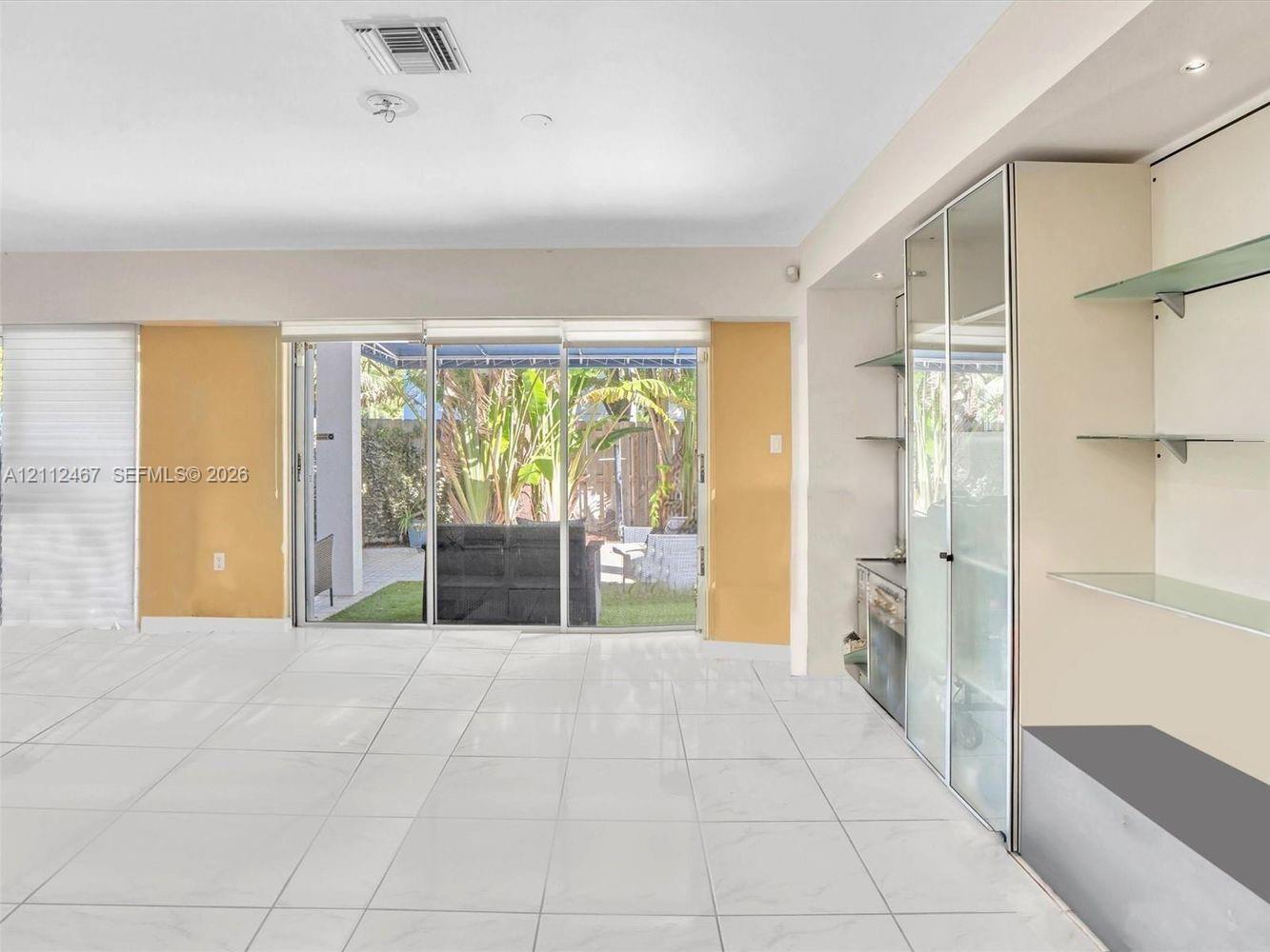 Large-format tile flooring, built-in shelving with glass display cabinets, and floor-to-ceiling sliding glass doors