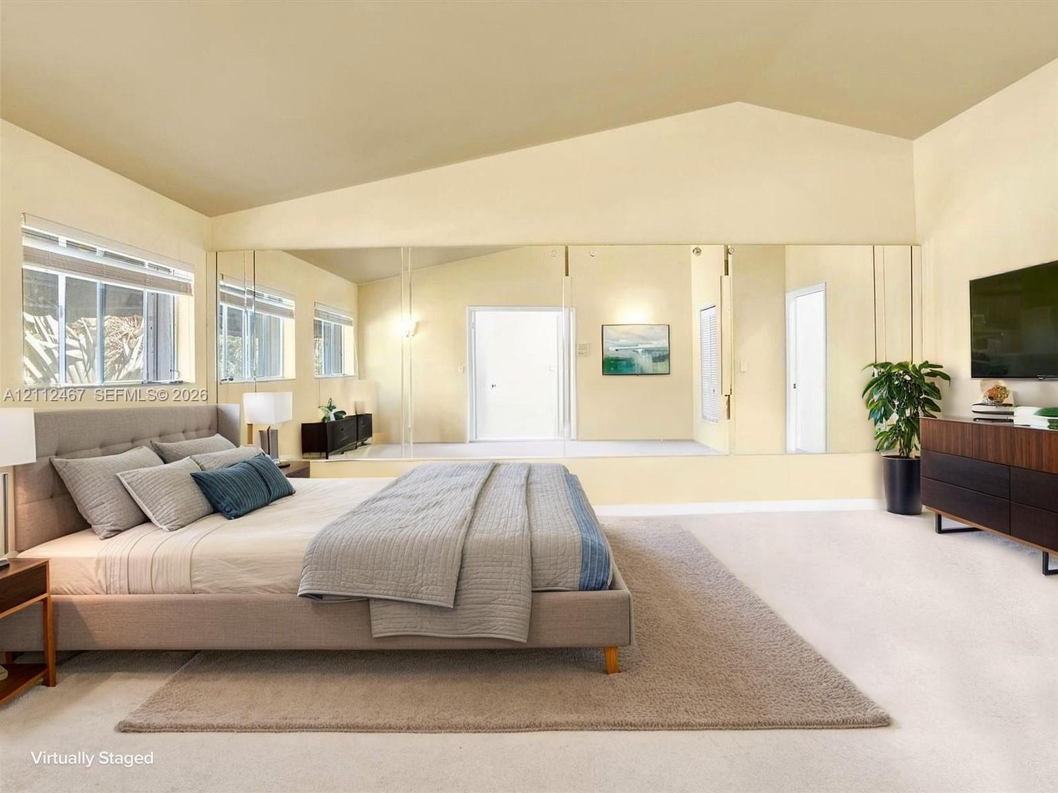 Vaulted ceiling, full-width wall mirror, and large windows with horizontal blinds