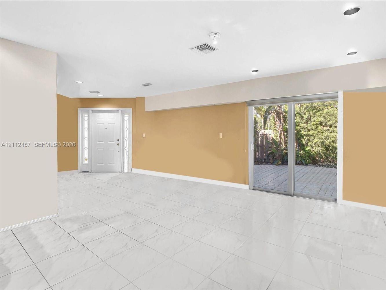 Neutral-toned interior featuring large-format tile flooring, recessed ceiling lighting, a multi-panel glass sliding door, and a paneled entry door with sidelights