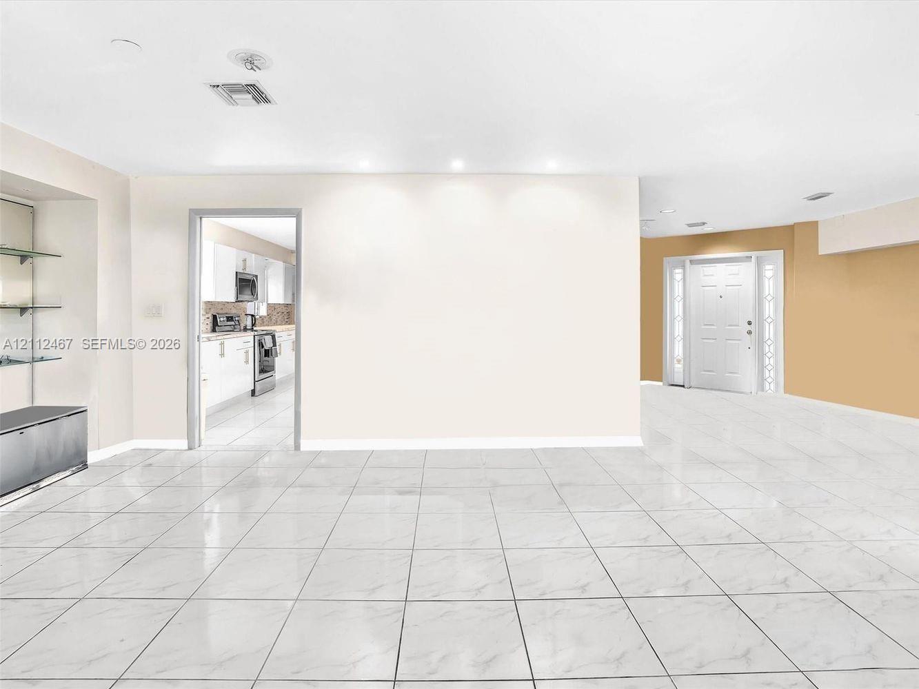 Large-format tile flooring, recessed ceiling lighting, built-in recessed display shelving, and an exterior entry door with glass sidelights