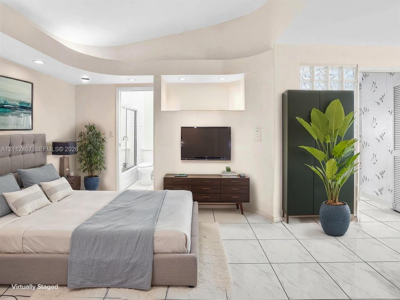 Tray ceiling with recessed lighting, large-format tile flooring, and glass block wall accent