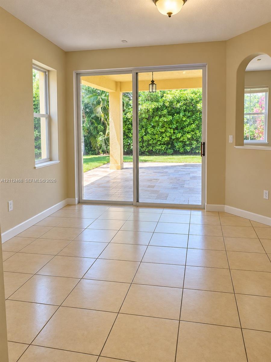 Tile flooring, sliding glass door, arched wall opening, and covered exterior patio with stone-finish pavers