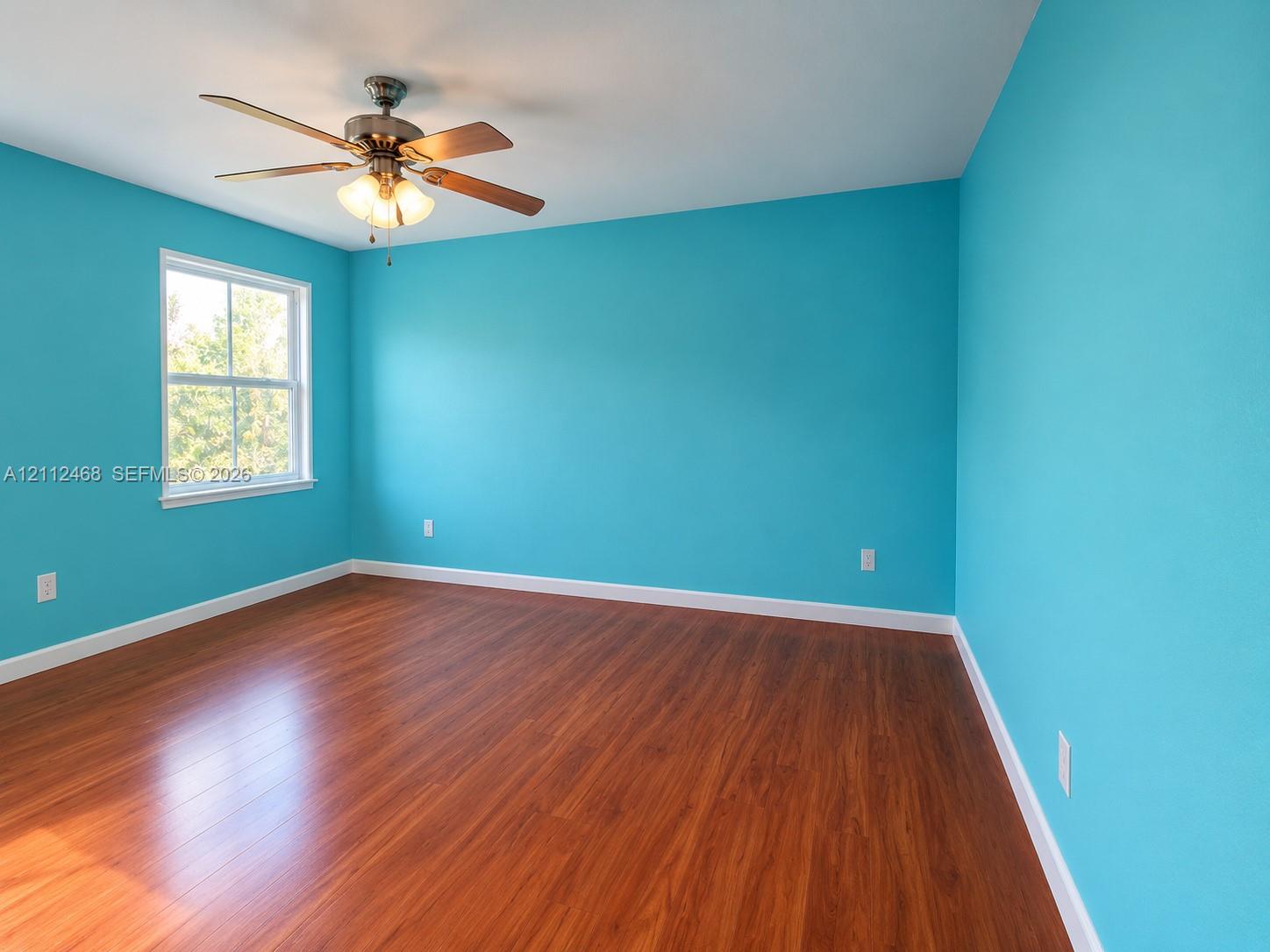 Room featuring wood-finish flooring, a ceiling fan with integrated lighting, and a single-hung window