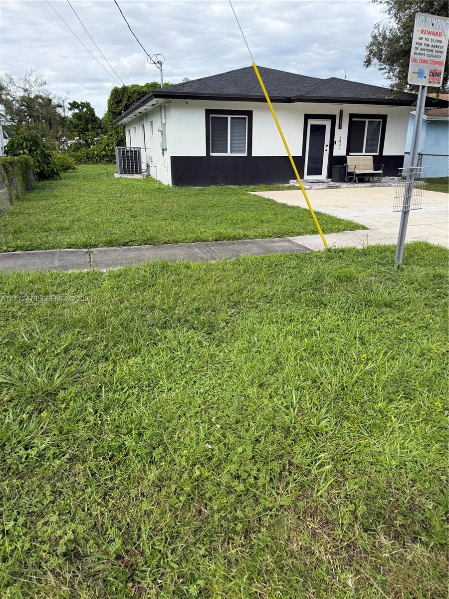 Single-story residence featuring high-contrast exterior finishes, a concrete driveway, and an expansive grass lawn