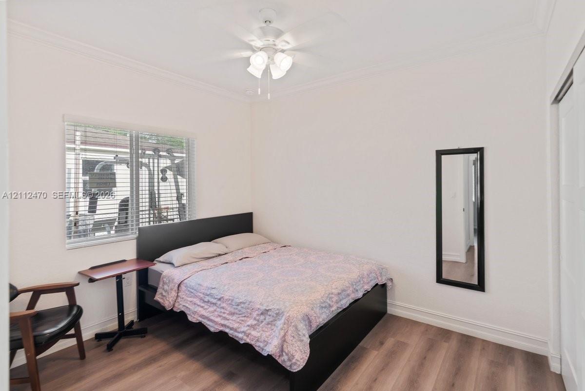 Room featuring wood-finish flooring, neutral wall paint, a multi-light ceiling fan, and horizontal window blinds