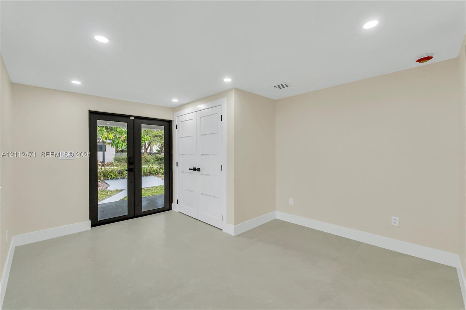 Interior space featuring recessed lighting, smooth-finish flooring, double-door closet with matte black hardware, and glass-paned double doors with dark framing