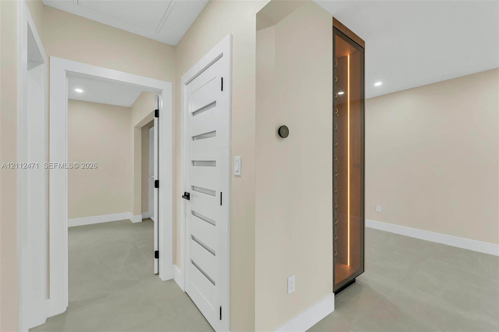Built-in glass-paneled display cabinet with integrated vertical lighting, solid-core interior doors with horizontal glass inserts, matte black hardware, and neutral-tone flooring