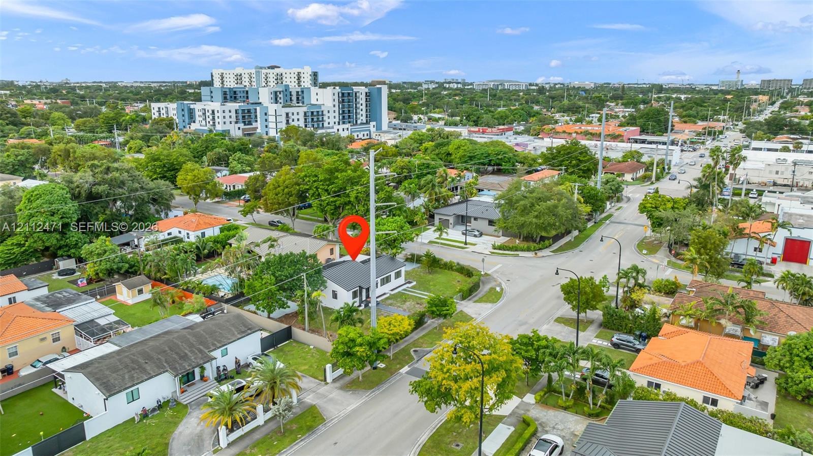 Aerial perspective of a detached property featuring a flat roofline, white exterior facade, landscaped grounds, and a fenced perimeter