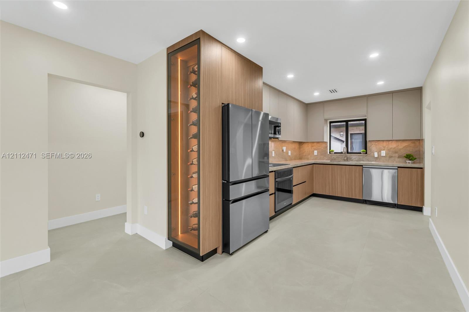 Kitchen featuring wood-finish cabinetry, stainless steel appliances, built-in temperature-controlled wine storage, stone tile backsplash, and recessed lighting