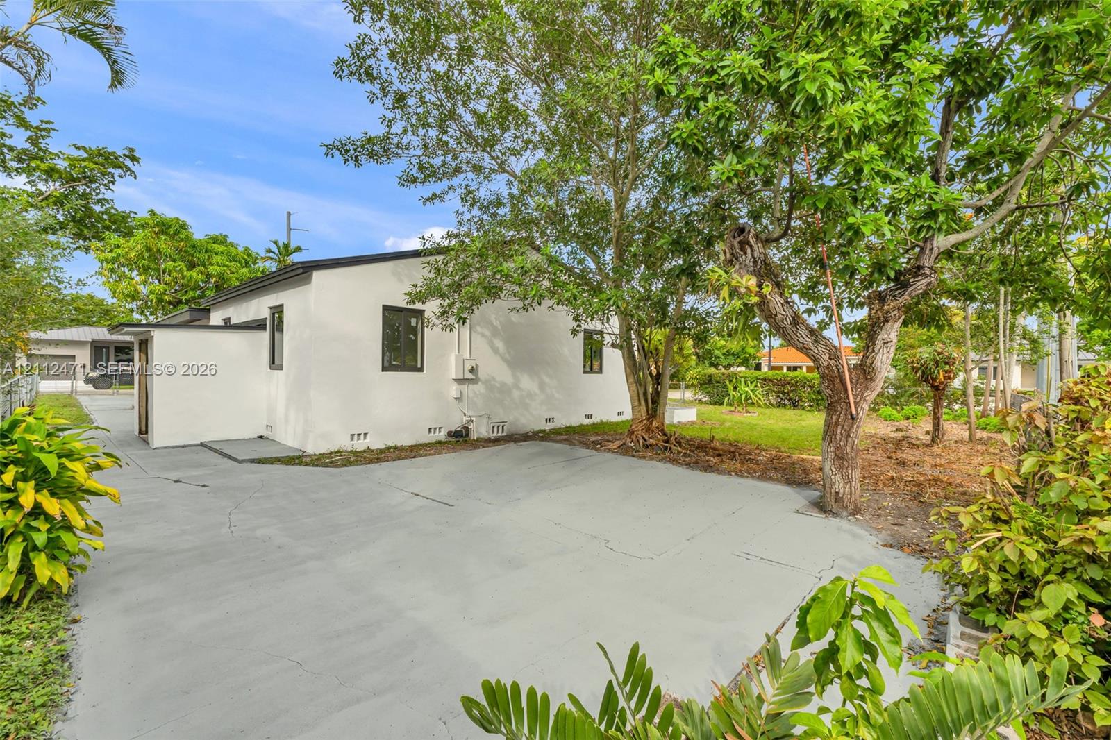Stucco exterior with a paved driveway, mature trees, and landscaping Stucco exterior with a paved driveway, mature trees, and landscaping