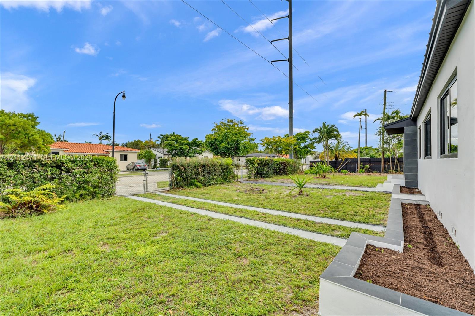 Side yard featuring manicured perimeter hedging, dual concrete paved paths, and multi-level masonry planter beds with dark tile capping Side yard featuring manicured perimeter hedging, dual concrete paved paths, and multi-level masonry planter beds with dark tile capping