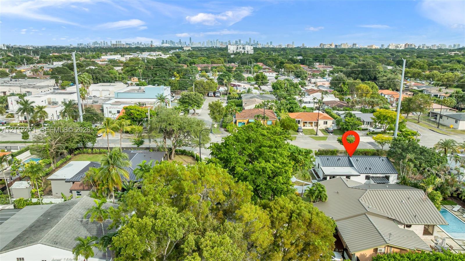 Aerial perspective featuring a metal roof system, mature landscaping, and an inground swimming pool