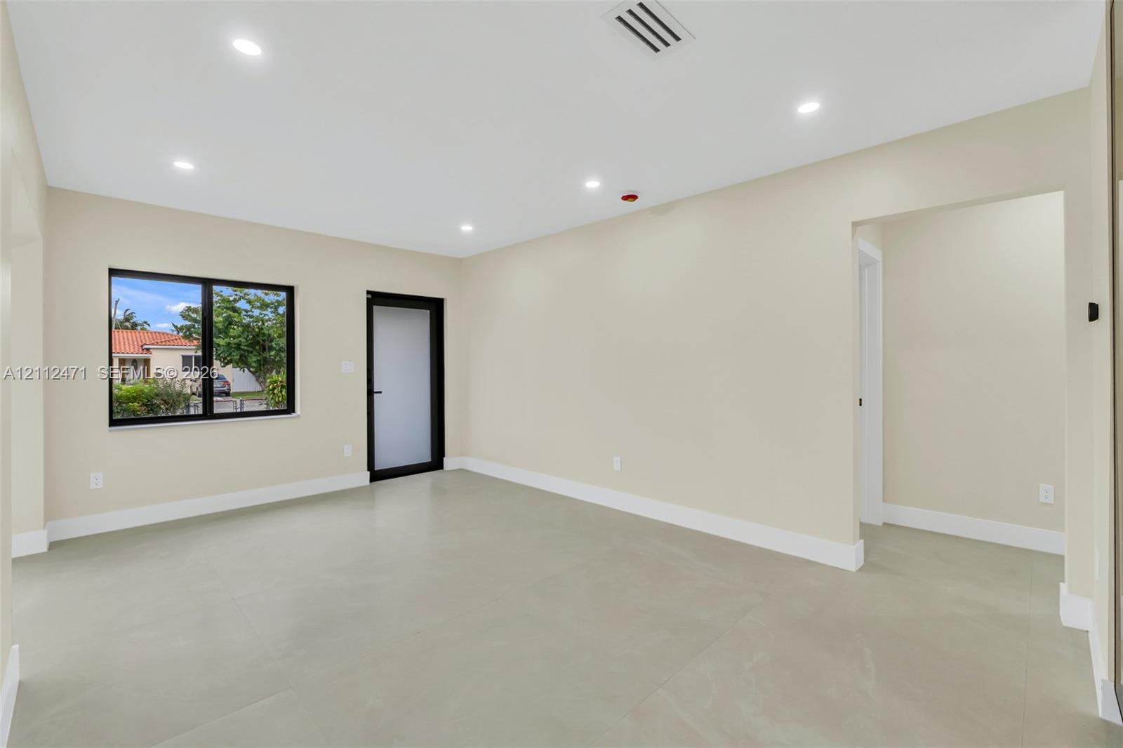 Open-concept room featuring neutral paint, large-format tile flooring, recessed ceiling lighting, and a door with frosted glass paneling
