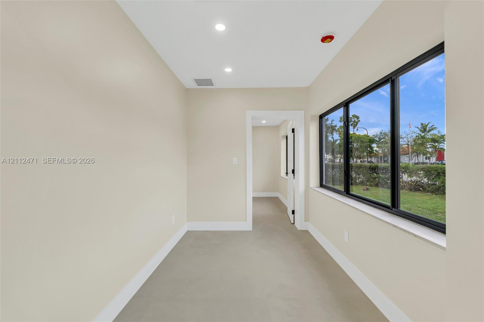 Interior space featuring neutral-toned walls, recessed lighting, polished concrete-finish flooring, and large windows with black frames