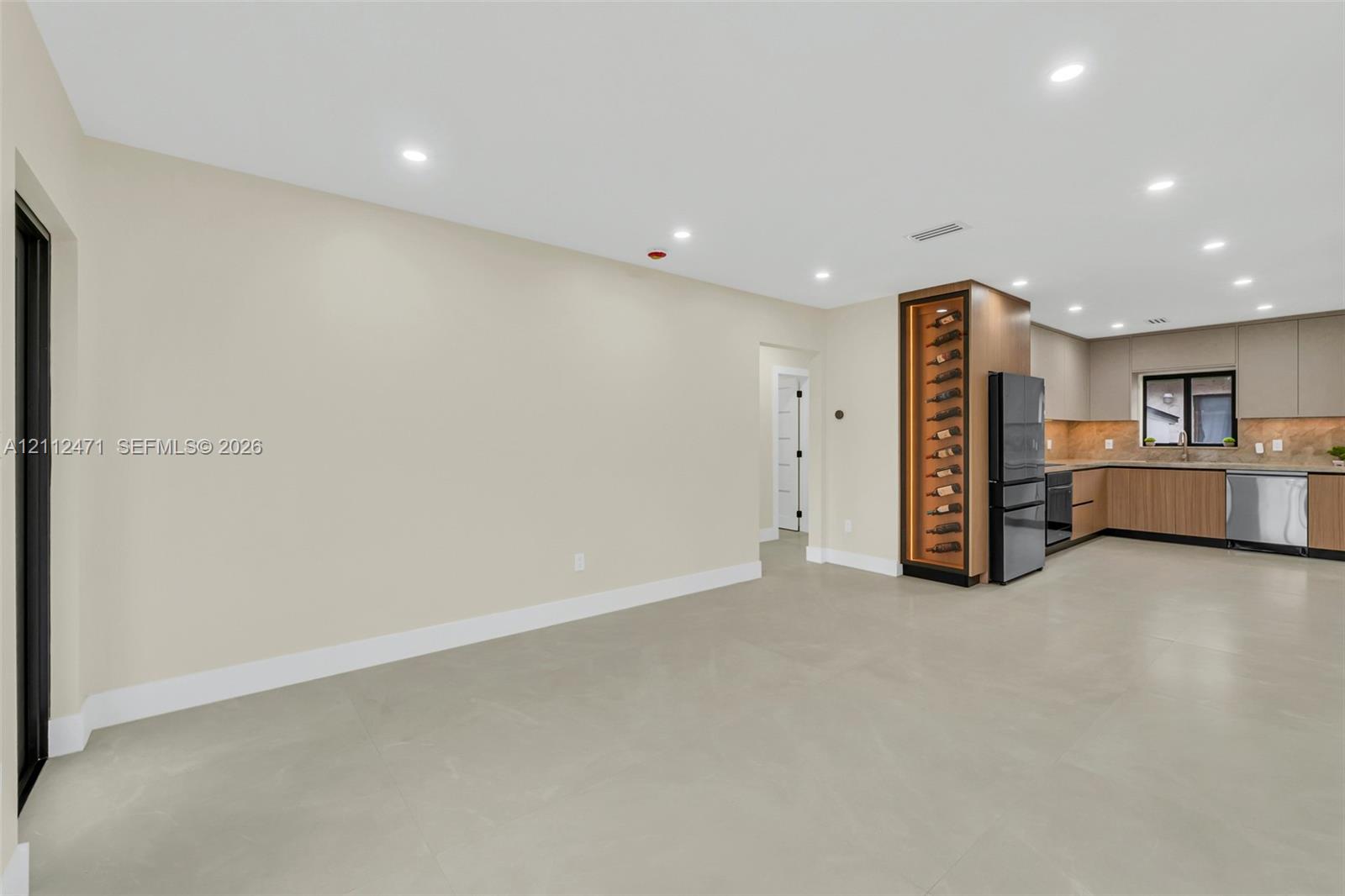 Kitchen featuring flat-panel wood cabinetry, recessed lighting, built-in wine storage, stainless steel appliances, and solid-surface flooring