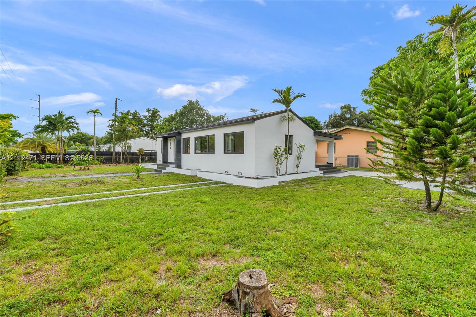 Single-story exterior featuring a white facade, black-framed windows, a flat roof, and a dual-track concrete driveway Single-story exterior featuring a white facade, black-framed windows, a flat roof, and a dual-track concrete driveway