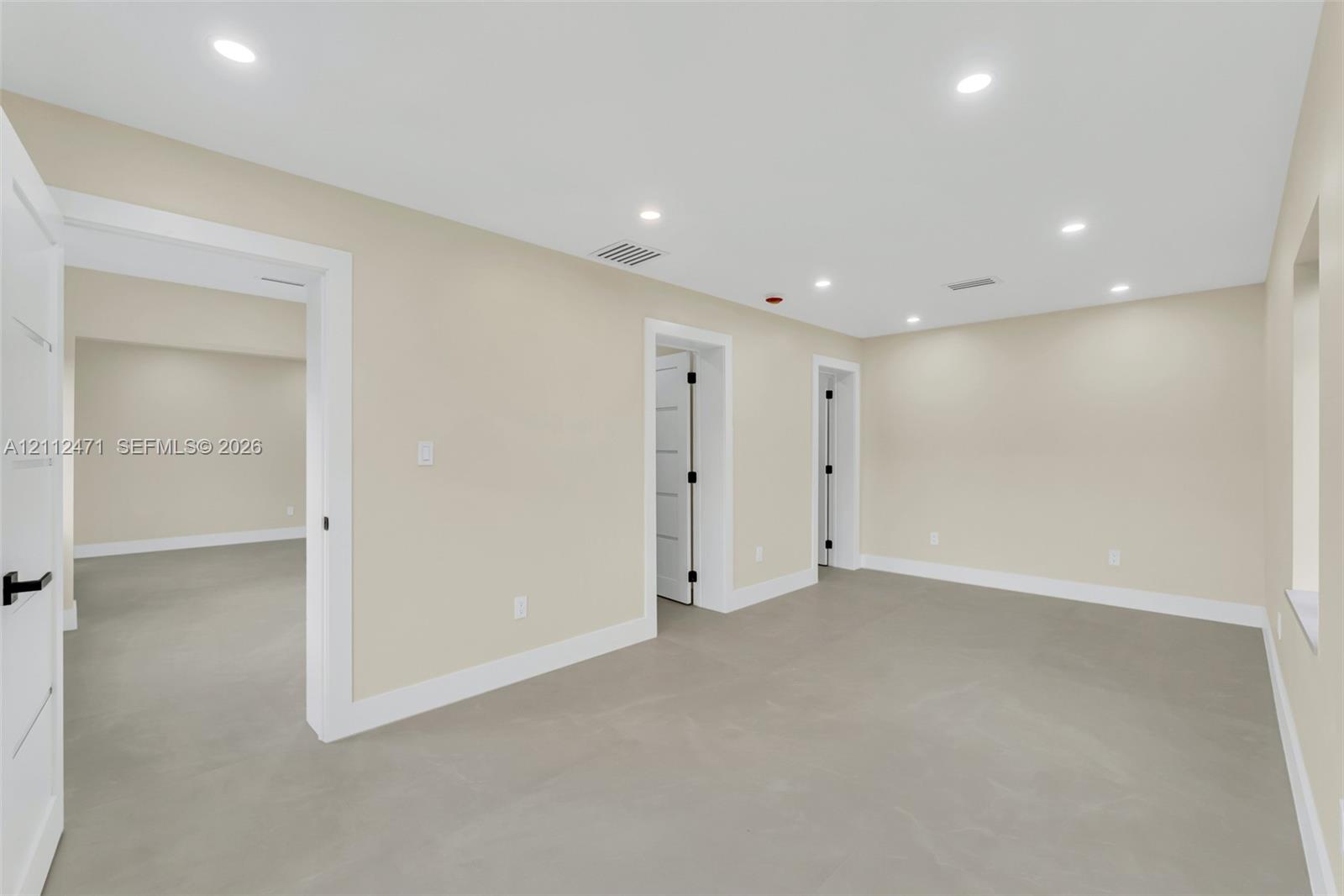 Interior room featuring recessed ceiling lighting, light-toned flooring, and multi-panel interior doors with matte black hardware