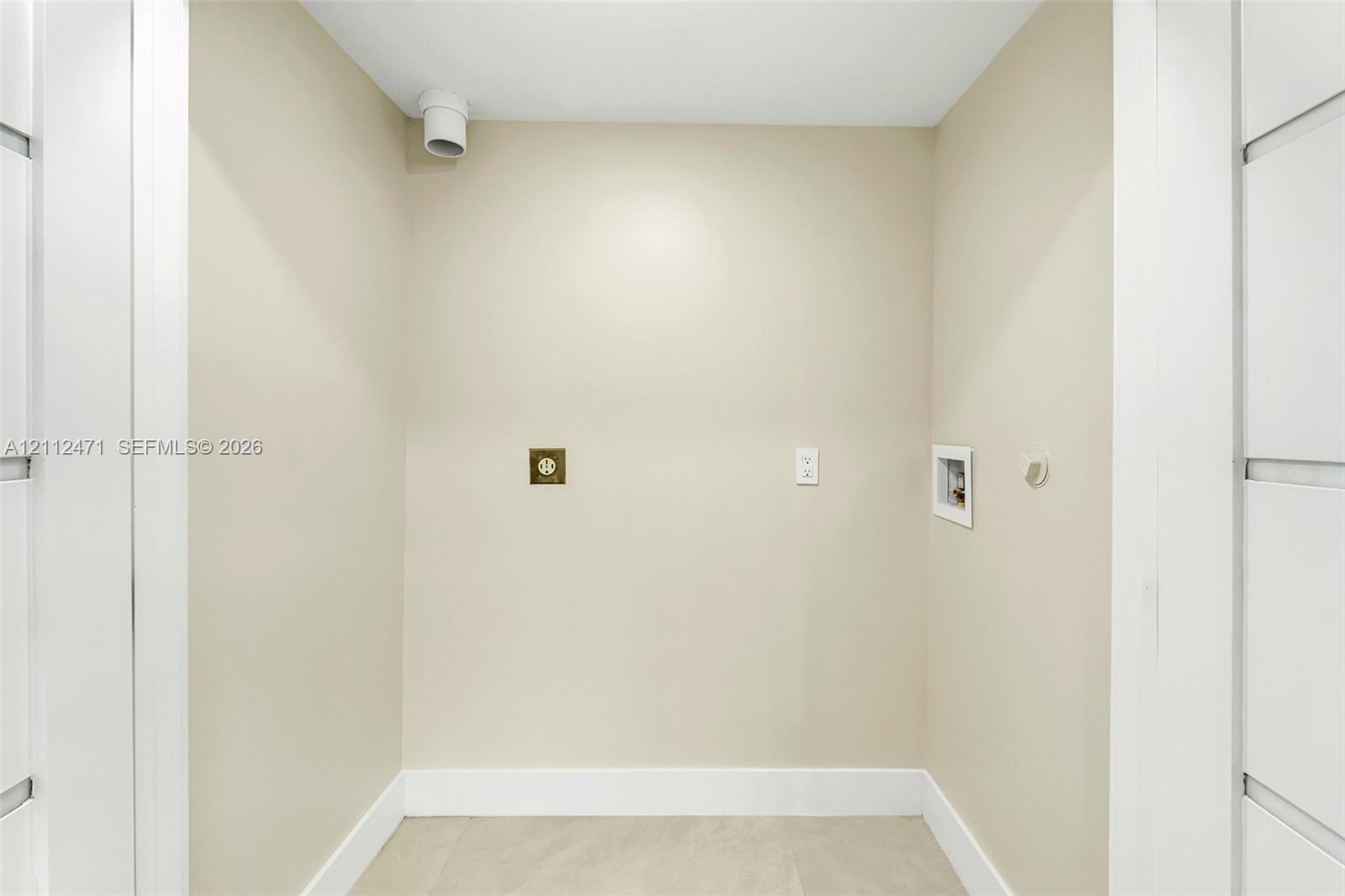 Dedicated utility alcove featuring neutral wall finishes, 220-volt electrical outlet, and plumbing hookups
