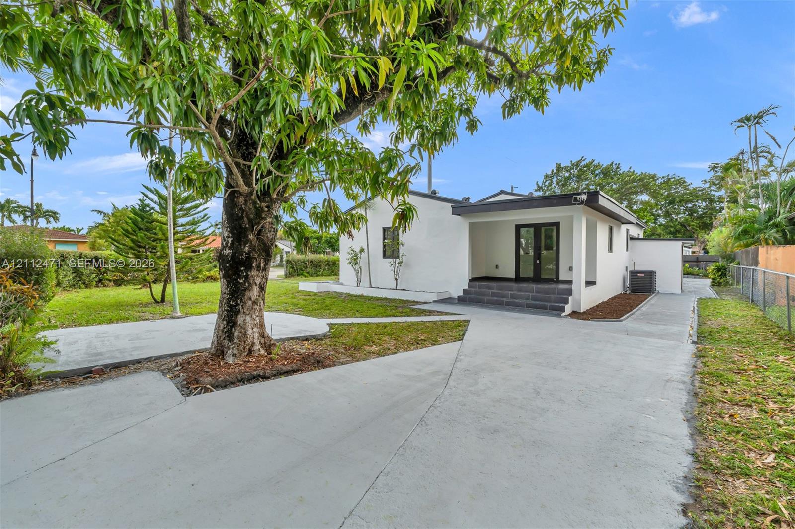 Exterior view featuring a white stucco facade, a covered porch with dark tile steps, and French doors