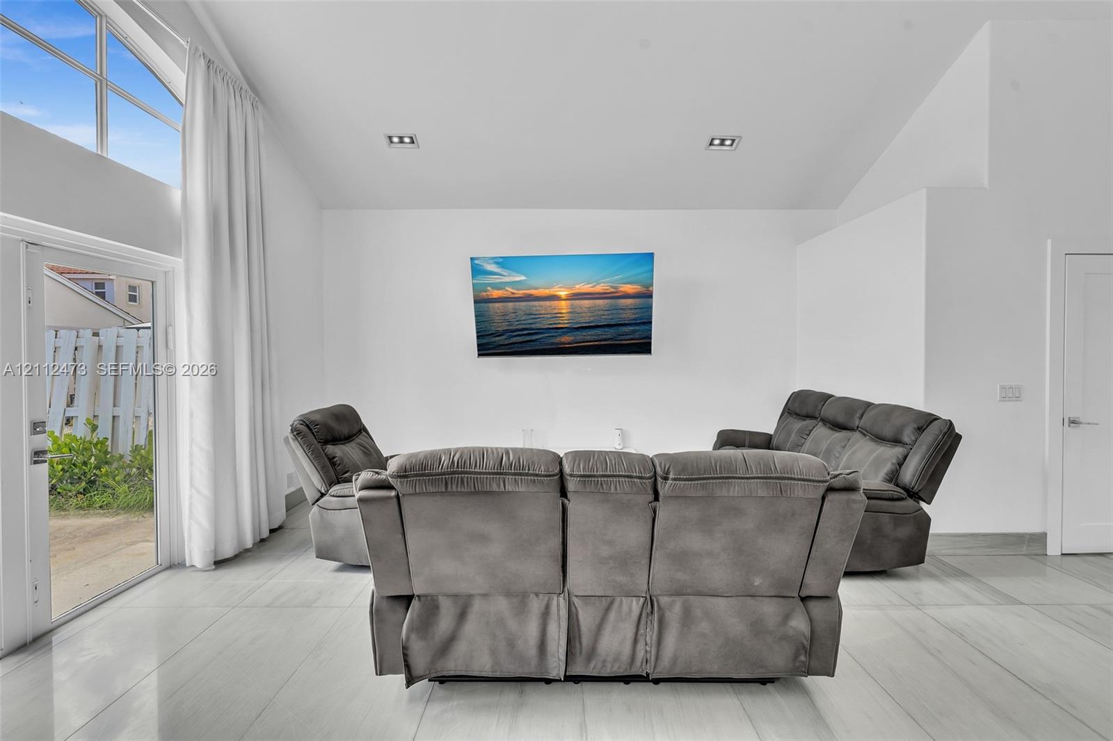 Vaulted ceiling featuring recessed lighting, large-format tile flooring, and floor-to-ceiling windows with glass exterior door