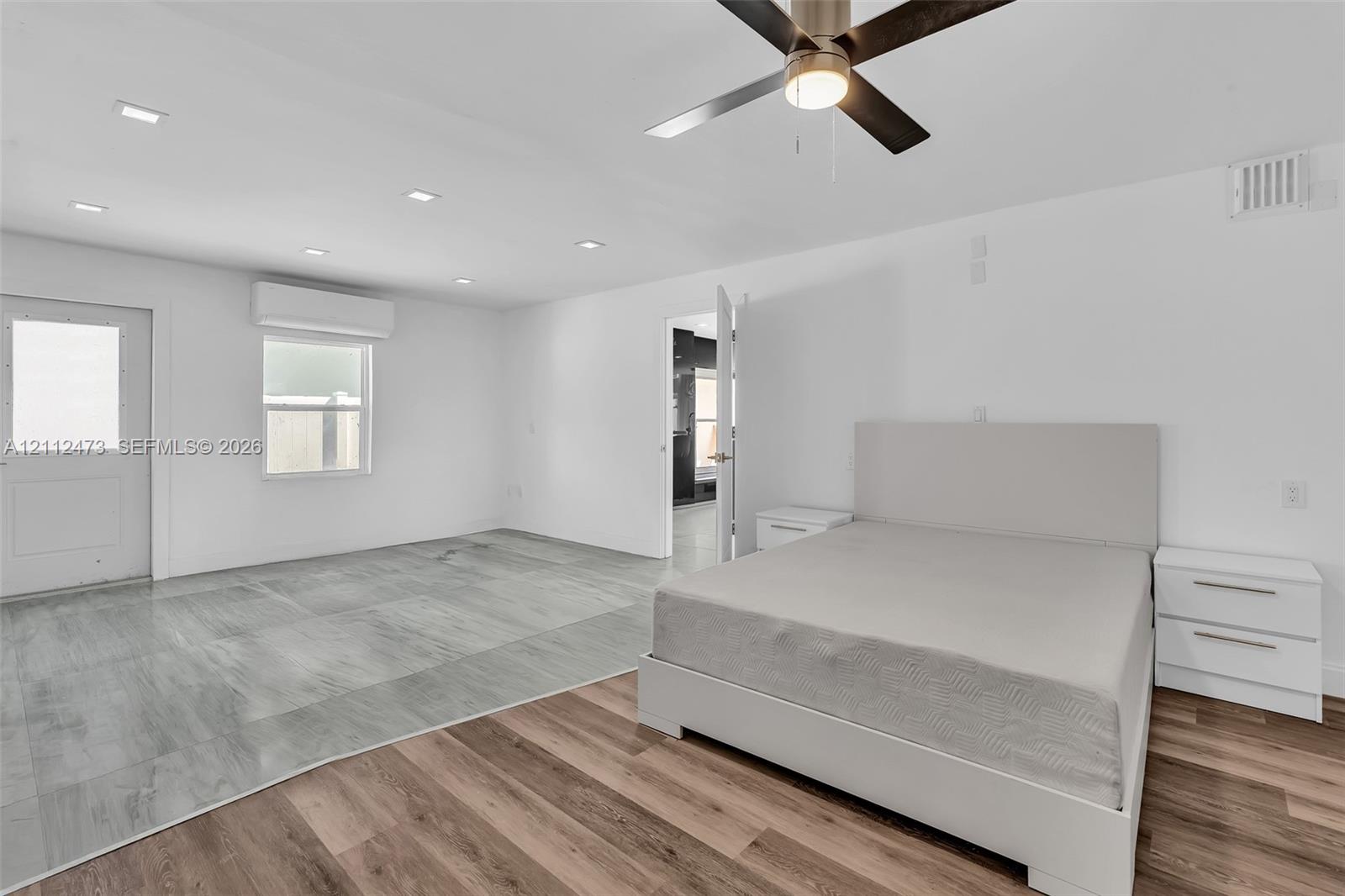 Interior space featuring wood-finish flooring, recessed lighting, ceiling fan with integrated light, and wall-mounted climate control unit
