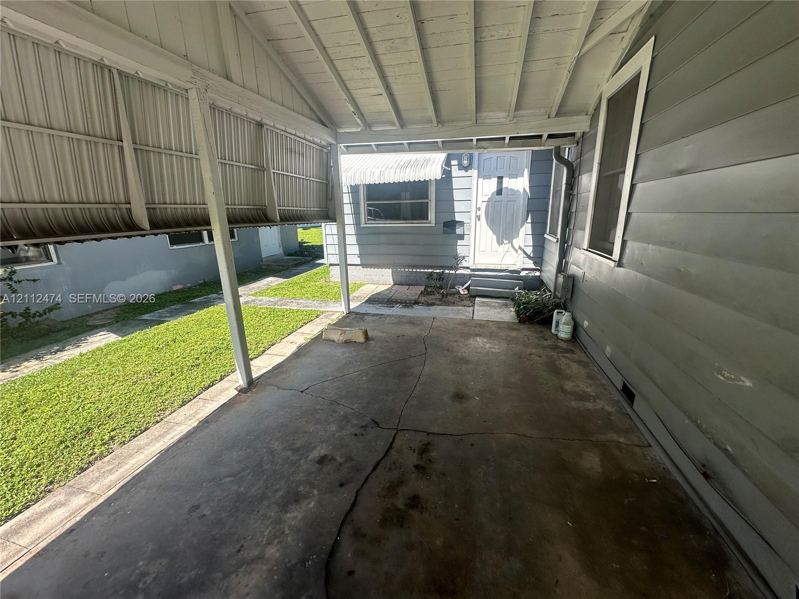 Covered carport featuring a concrete floor, horizontal siding, and a metal roof structure