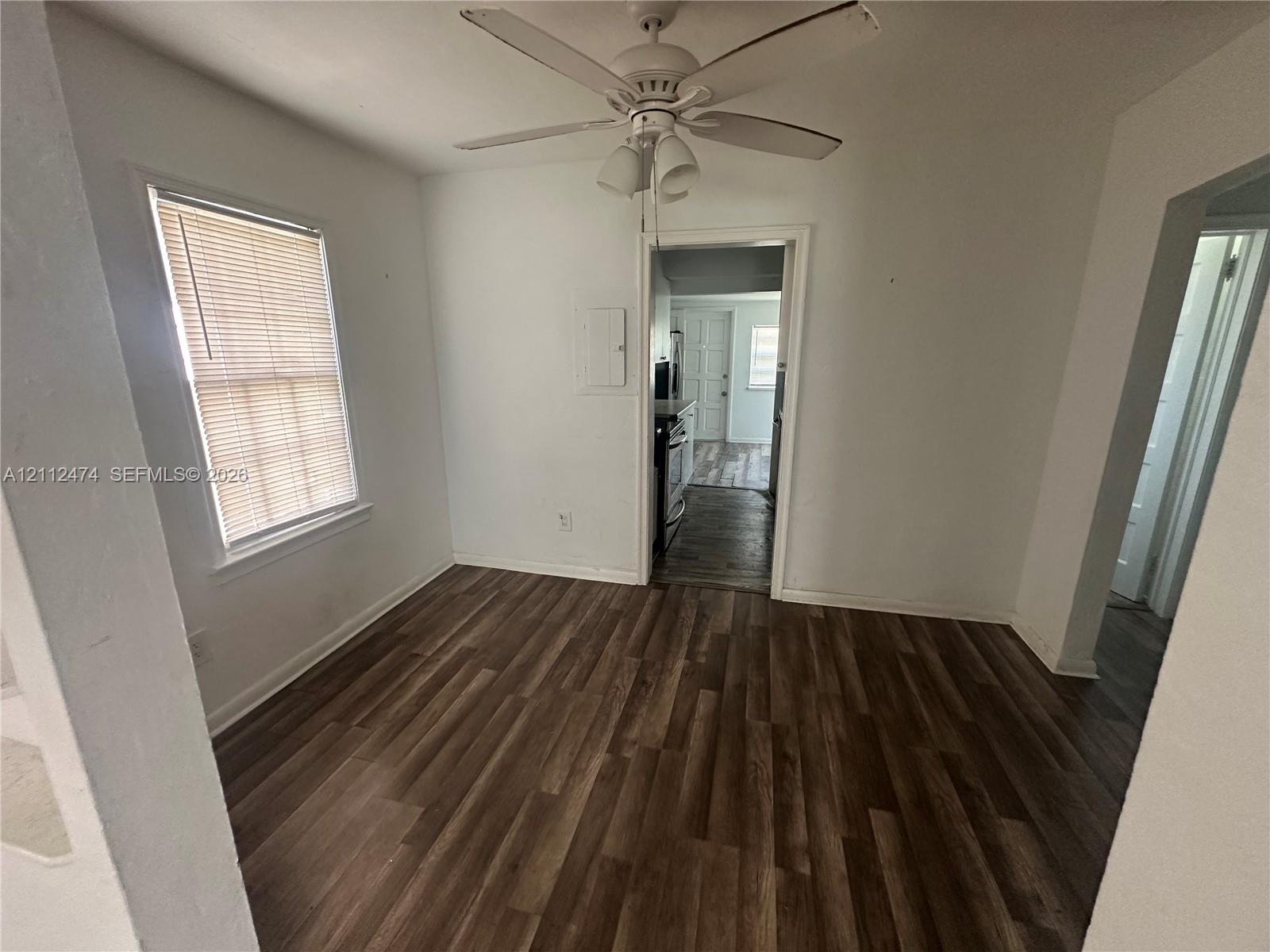 Interior space featuring wood-finish flooring, a ceiling fan with integrated lighting, and a single-pane window with blinds