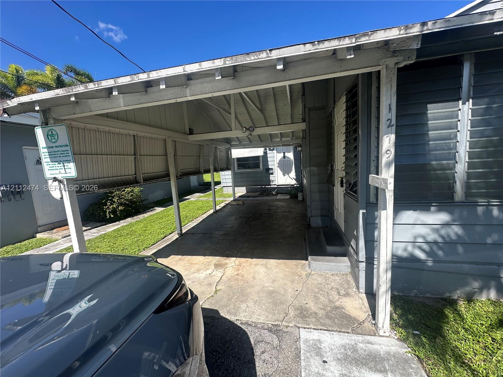 Attached carport with concrete flooring, exposed beam ceiling structure, and metal siding Attached carport with concrete flooring, exposed beam ceiling structure, and metal siding