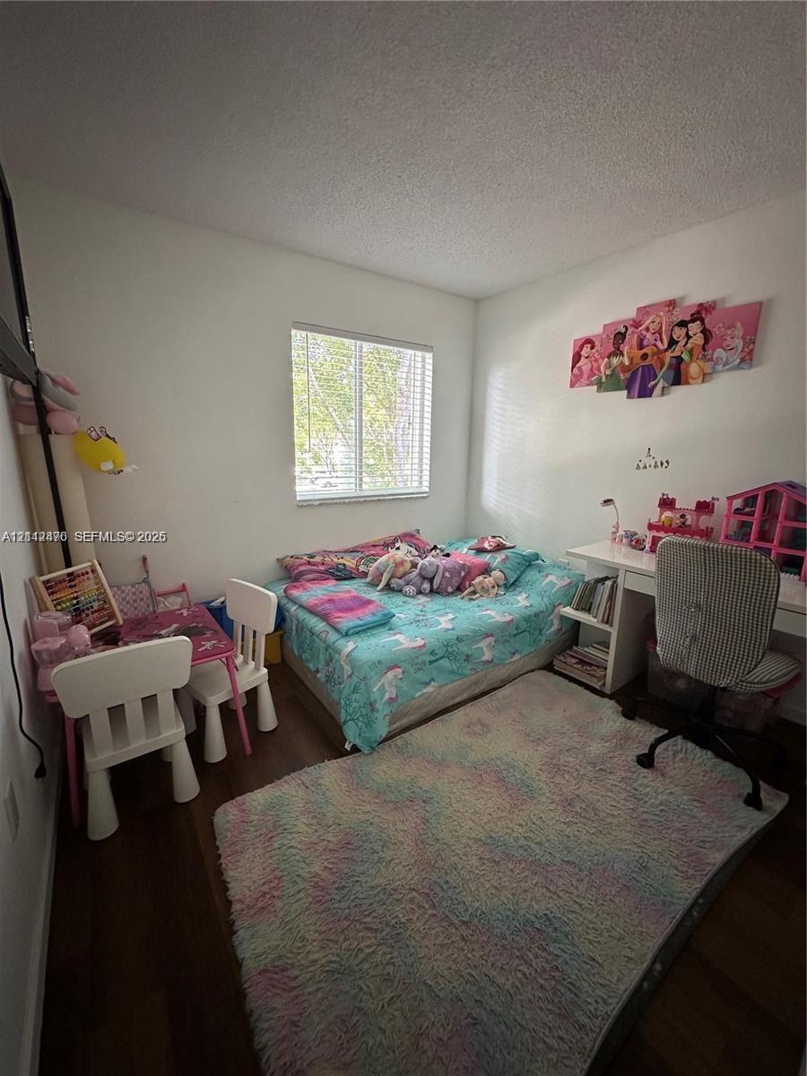 Bedroom featuring wood-finish flooring and a single-pane horizontal sliding window