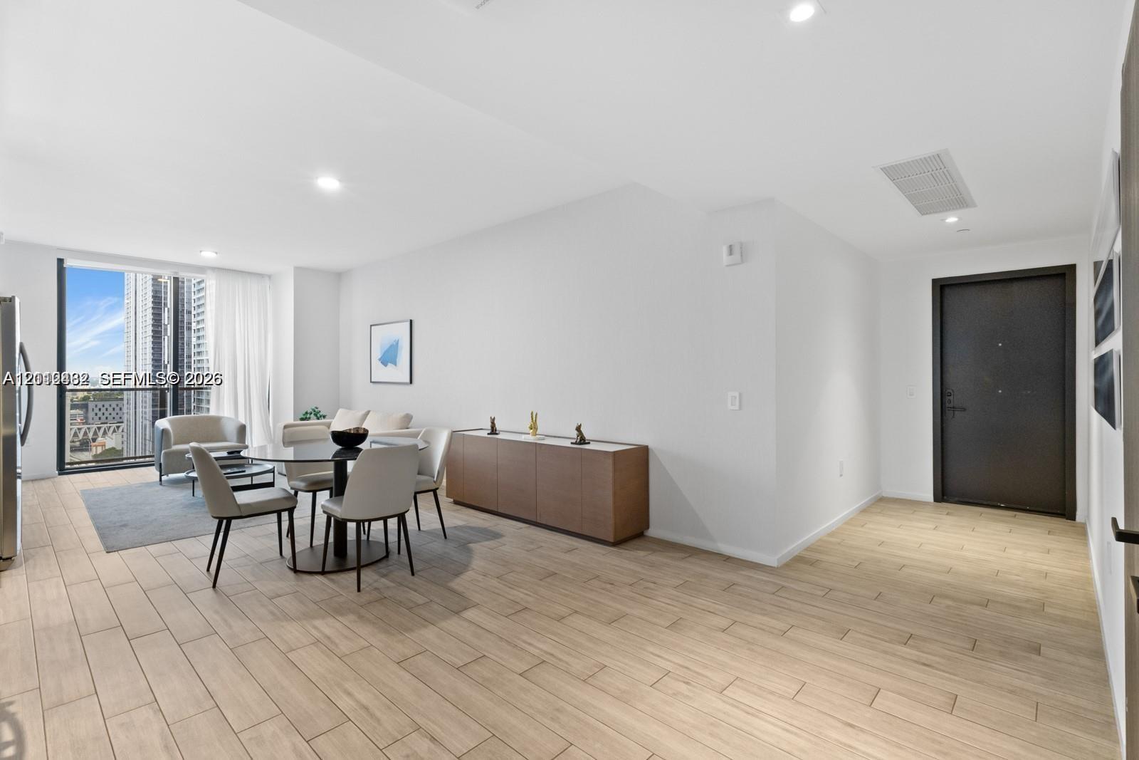 Open-concept area featuring wood-finish tile flooring, recessed ceiling lighting, and floor-to-ceiling windows