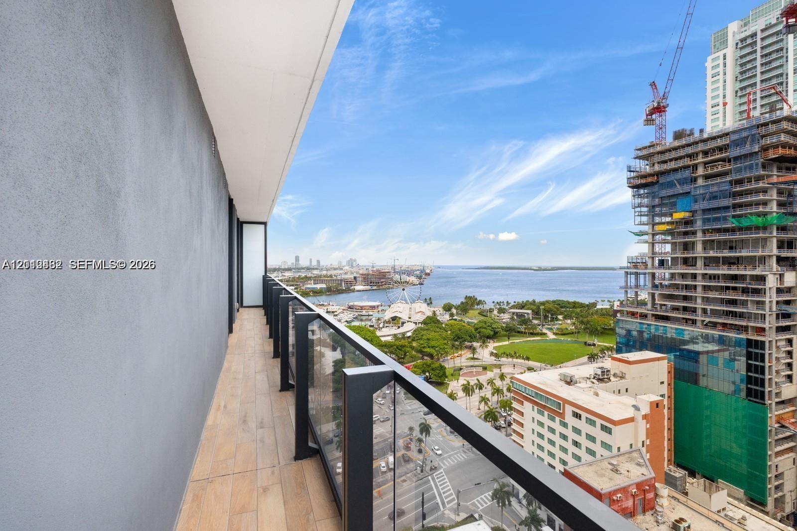 Covered balcony featuring wood-finish flooring, solid partition walls, and a glass-panel railing