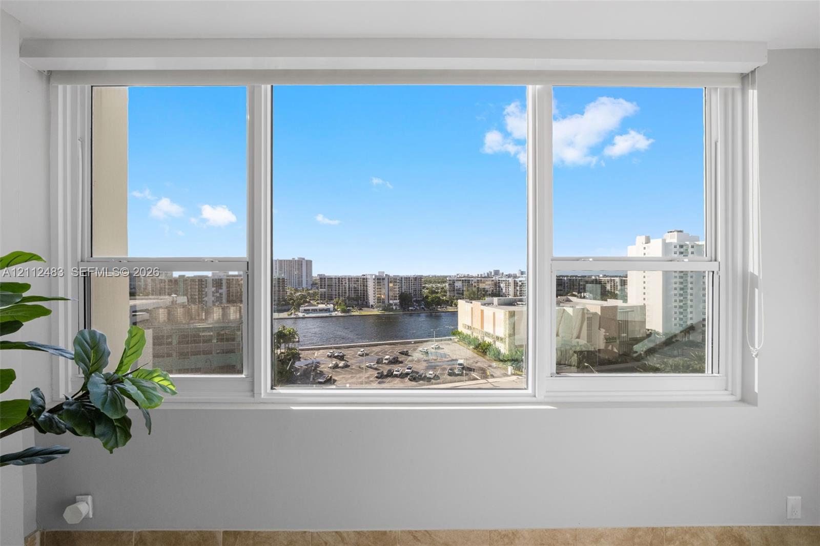 Large triple-pane window featuring white frames and a wide sill, showcasing expansive water and urban scenery