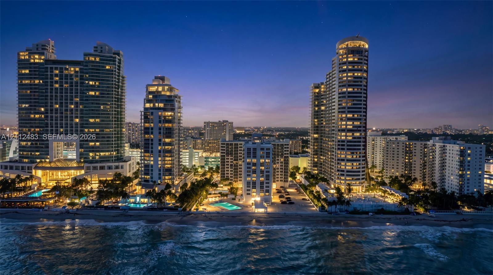 Coastal high-rise residential complex featuring oceanfront positioning, multiple swimming pools, and landscaped grounds with mature palm trees