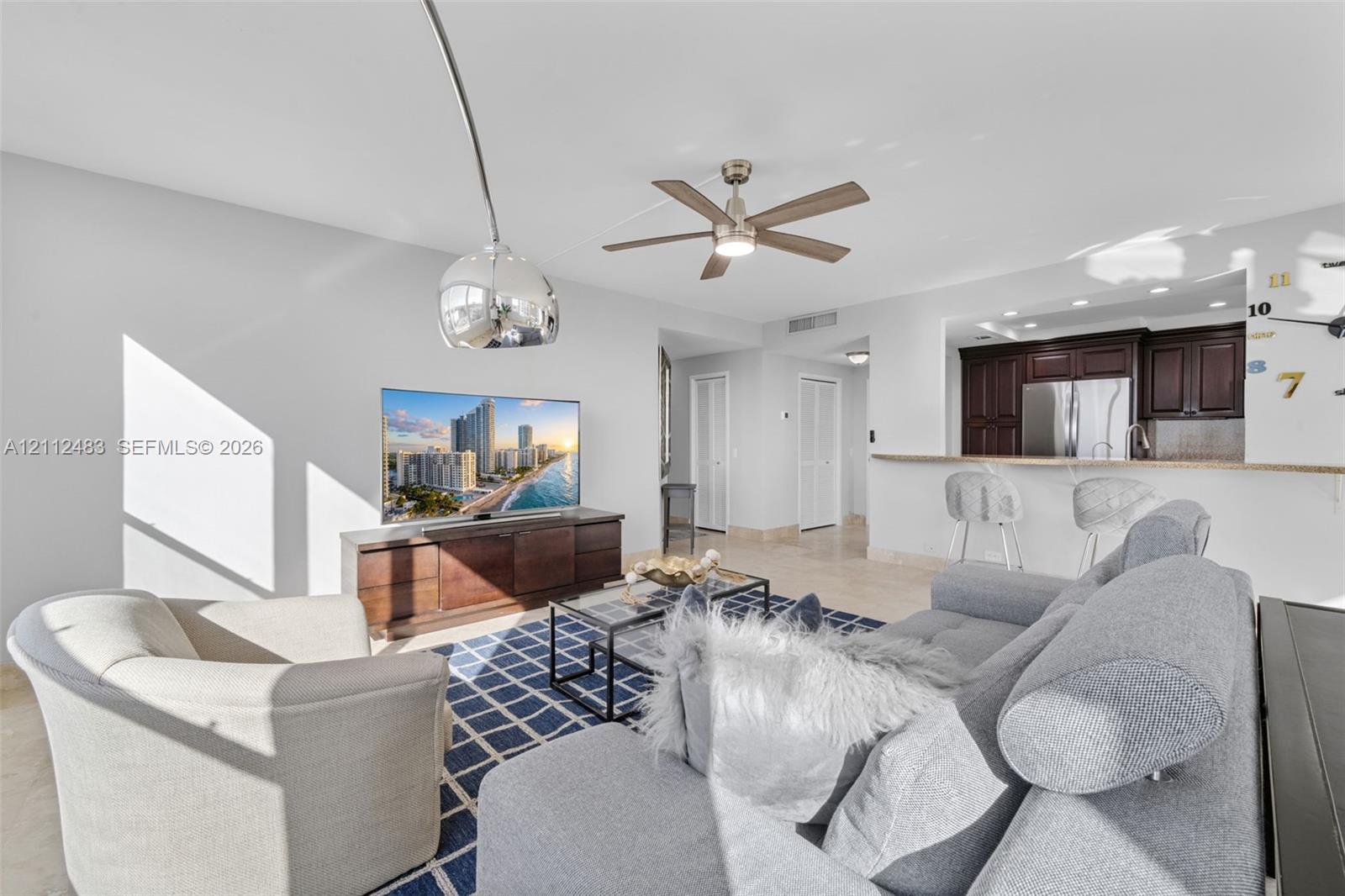 Open-concept space featuring recessed lighting, a modern ceiling fan, tile flooring, and kitchen cabinetry with a breakfast bar