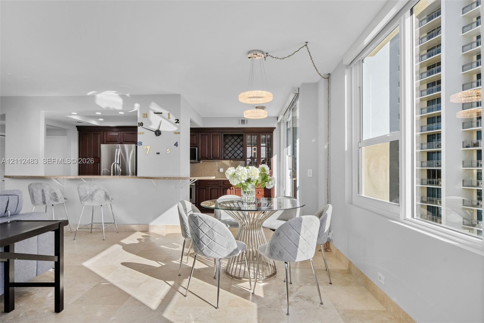 Open-concept kitchen featuring dark wood cabinetry, a pass-through breakfast bar with a stone countertop, stone flooring, and dual pendant light fixtures
