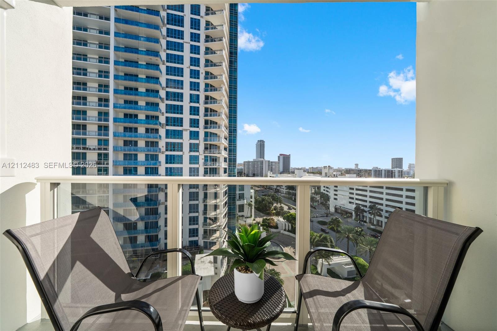 Private balcony featuring a glass panel railing and high-rise urban surroundings
