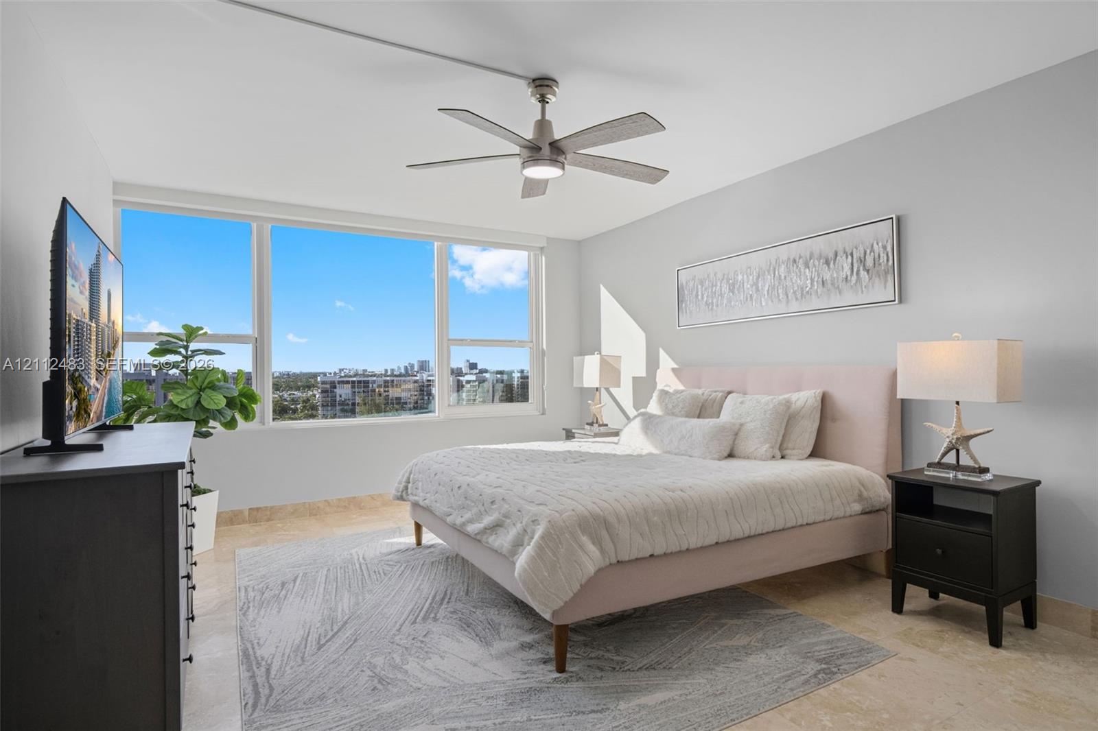 Neutral-toned room featuring expansive windows, stone flooring, and a modern ceiling fan with an integrated light fixture
