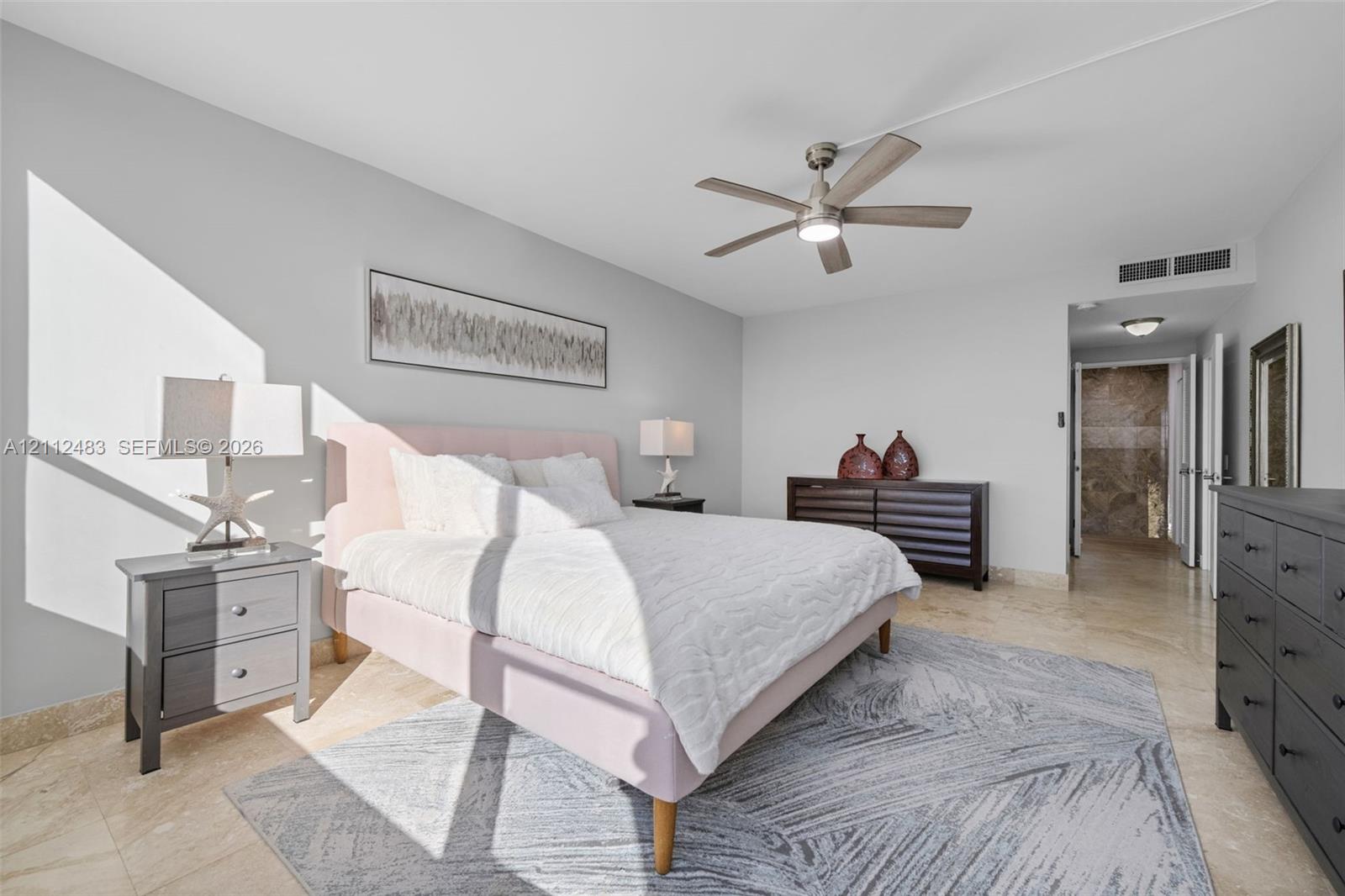 Neutral-toned room featuring large-format tile flooring, a brushed nickel ceiling fan with integrated lighting, and smooth-finish walls