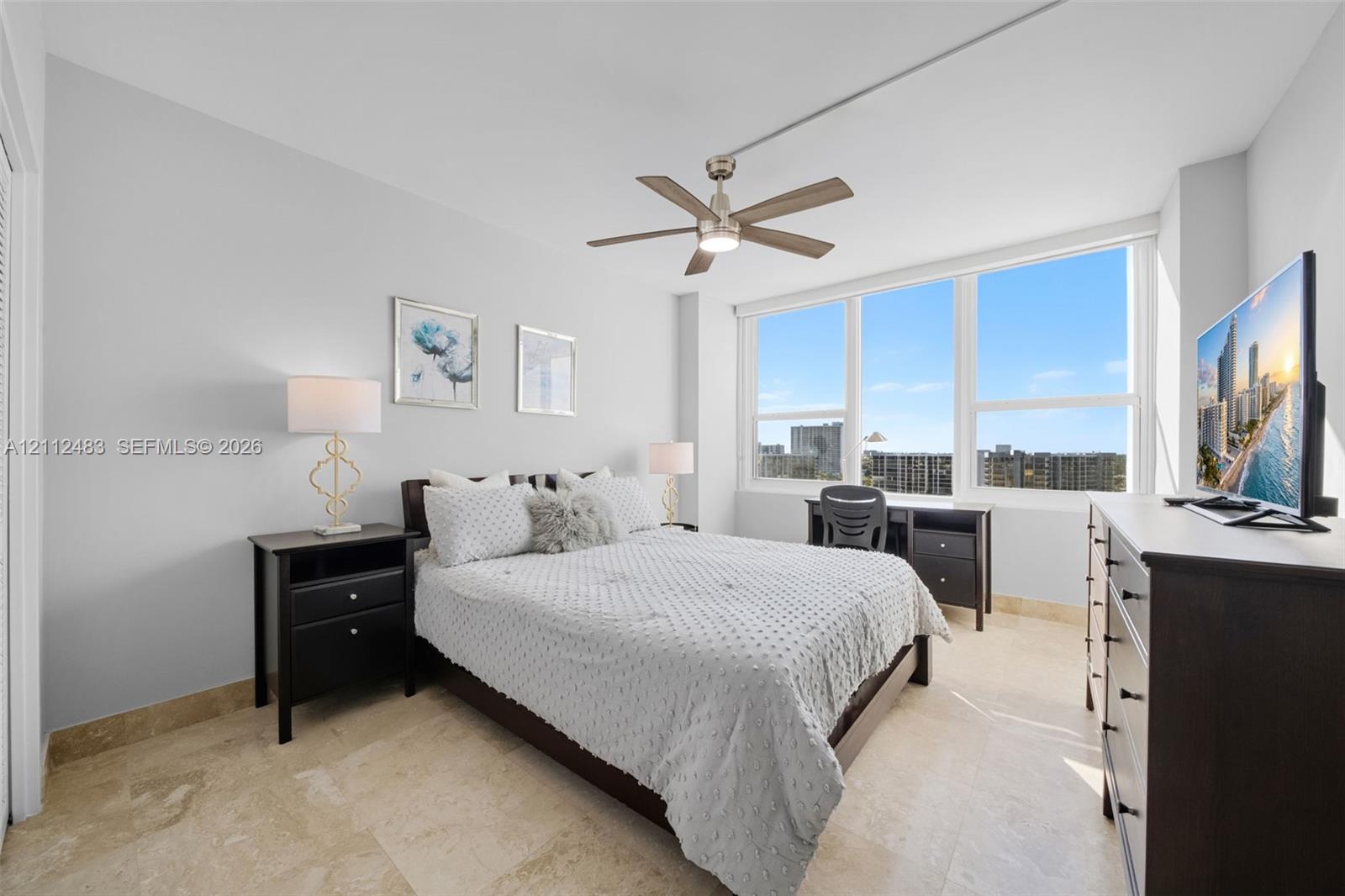 Neutral-toned tile flooring, floor-to-ceiling windows, and a multi-blade ceiling fan with integrated lighting