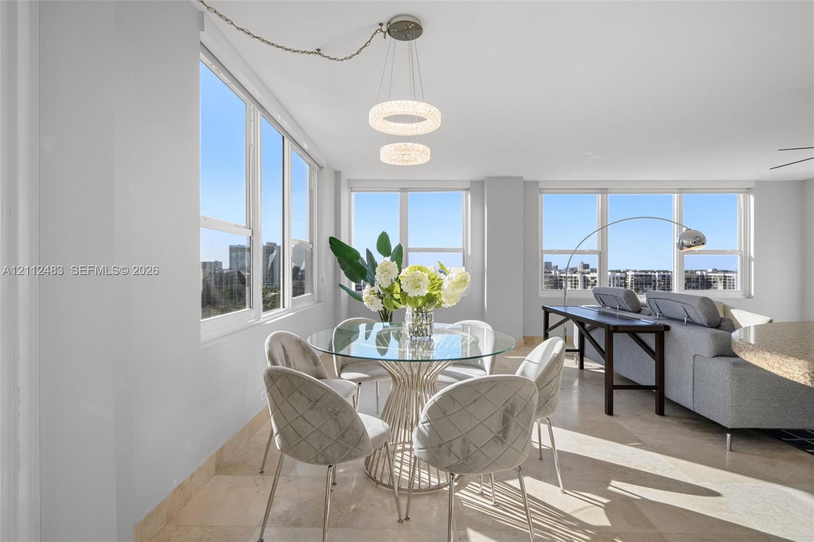 Open-concept interior featuring large-format stone flooring, floor-to-ceiling windows, and dual circular LED pendant lighting