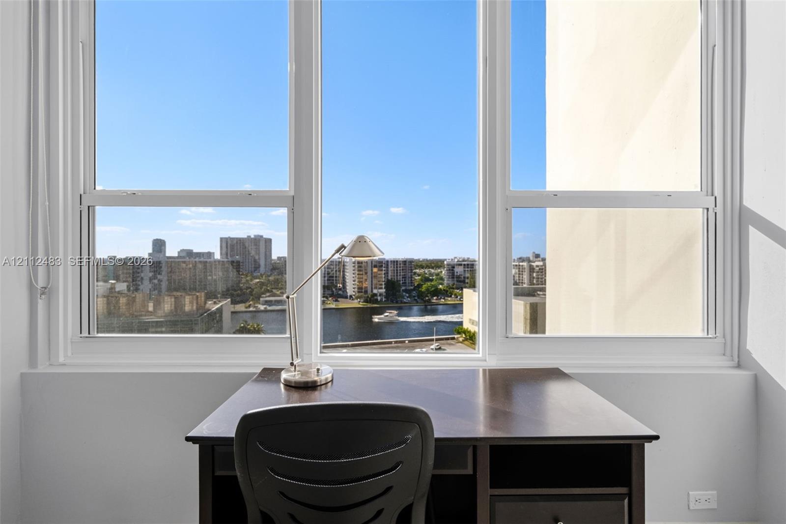 Large multi-pane window with white framing, providing natural light and exterior water and cityscape scenery