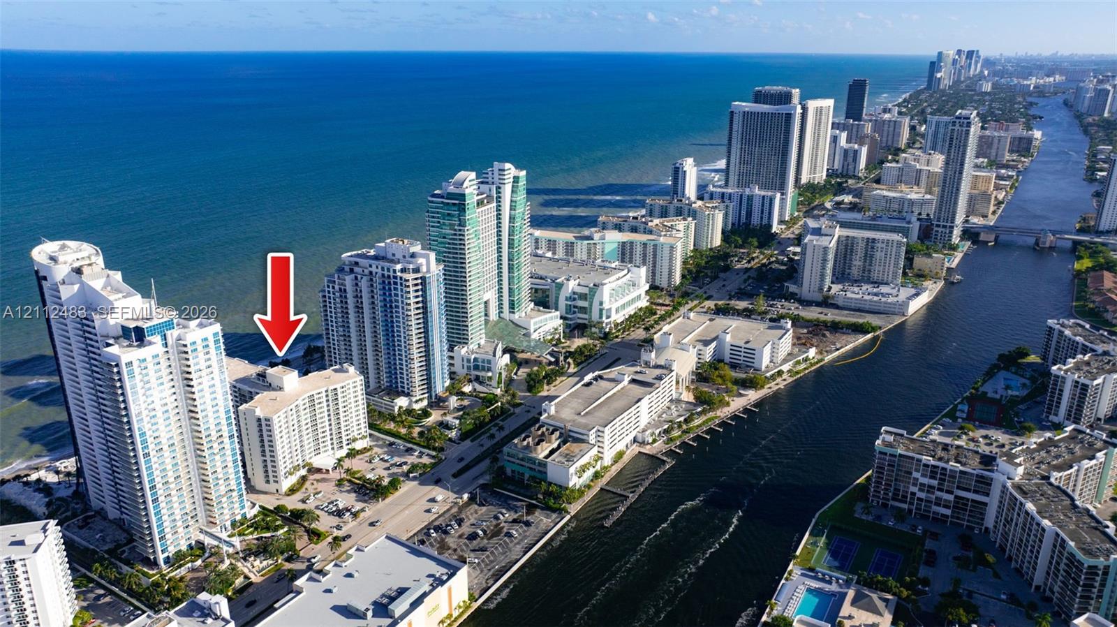 Aerial perspective of a high-rise residential building situated on the Atlantic coastline, featuring immediate proximity to the ocean, coastal waterway access, and urban infrastructure